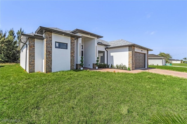 prairie-style house with stucco siding, an attached garage, driveway, and a front lawn