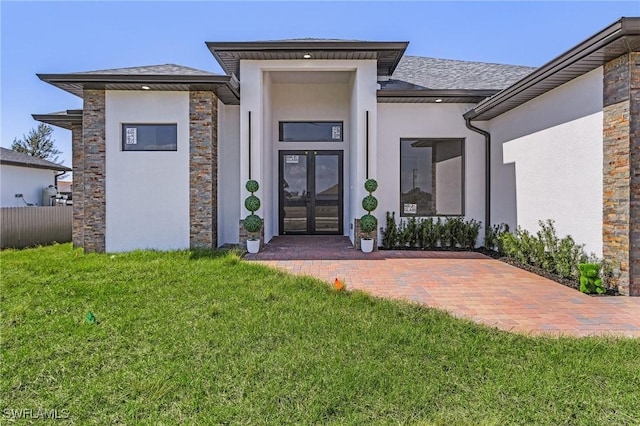 property entrance featuring stone siding, stucco siding, french doors, and a yard