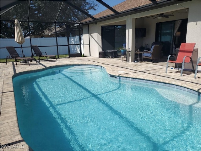 view of pool with ceiling fan, glass enclosure, and a patio area