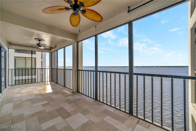 unfurnished sunroom with a water view and a ceiling fan