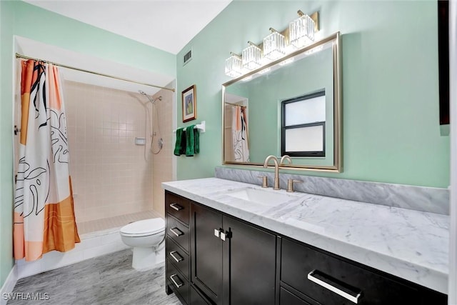 bathroom with visible vents, tiled shower, toilet, wood finished floors, and vanity