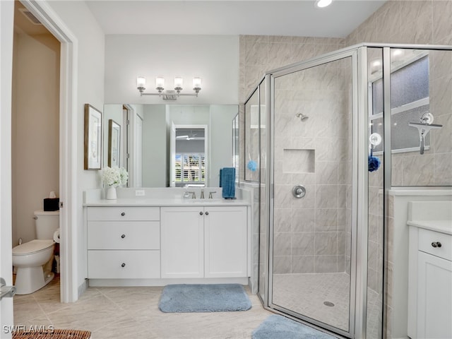 bathroom featuring a shower with door, vanity, and toilet