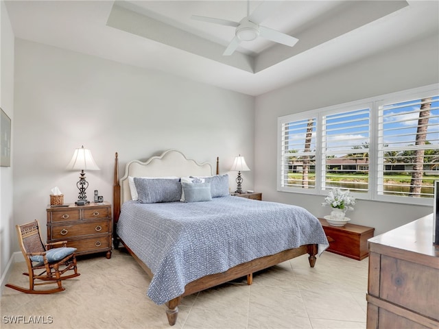 bedroom featuring ceiling fan, a tray ceiling, and light tile patterned floors