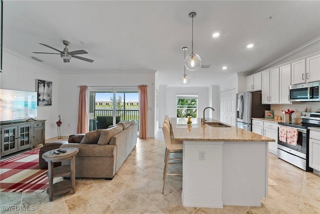 kitchen featuring sink, white cabinetry, hanging light fixtures, an island with sink, and stainless steel appliances