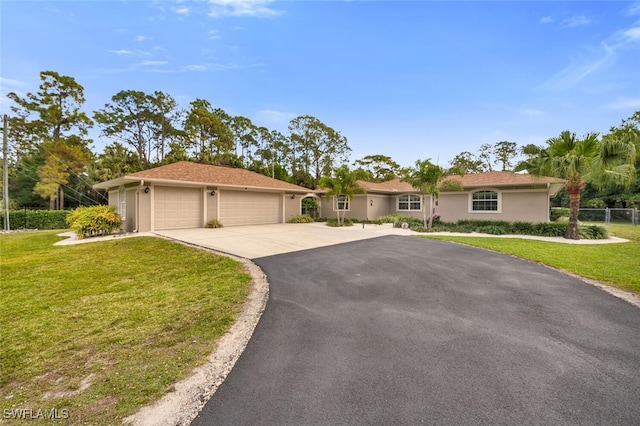 ranch-style home with stucco siding, driveway, fence, a front yard, and a garage