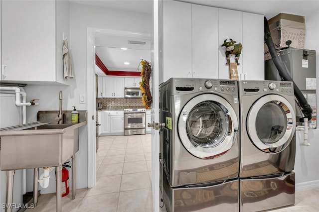 laundry room with washing machine and dryer, light tile patterned floors, recessed lighting, cabinet space, and a sink