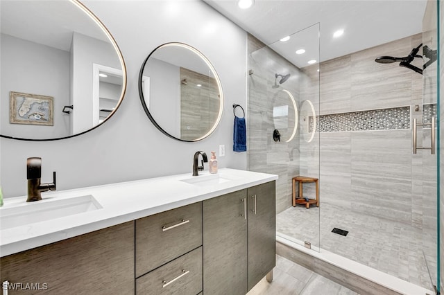 bathroom with double vanity, recessed lighting, a tile shower, and a sink