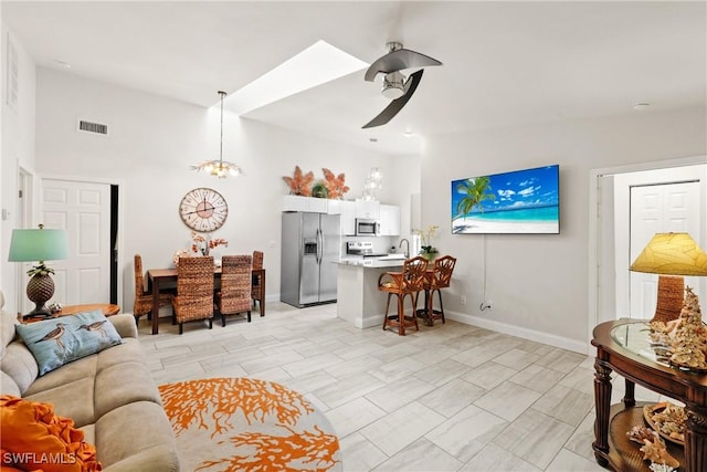 living room featuring vaulted ceiling and ceiling fan with notable chandelier