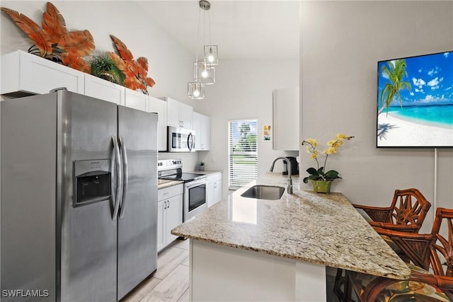 kitchen with appliances with stainless steel finishes, kitchen peninsula, sink, and white cabinets