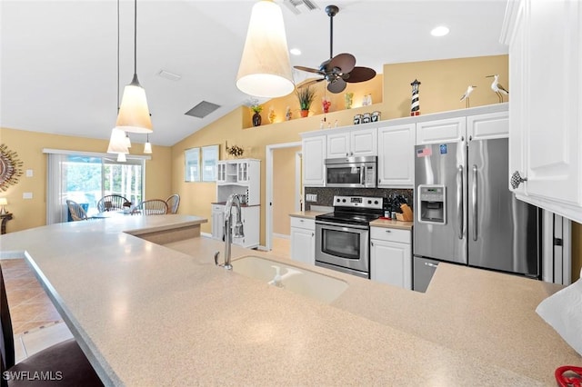 kitchen with decorative light fixtures, white cabinetry, lofted ceiling, sink, and stainless steel appliances