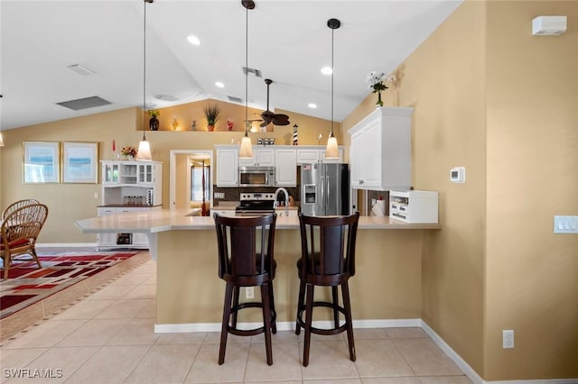 kitchen featuring appliances with stainless steel finishes, a breakfast bar, hanging light fixtures, and white cabinets