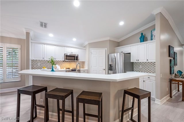 kitchen featuring a center island with sink, white cabinetry, stainless steel appliances, and light countertops