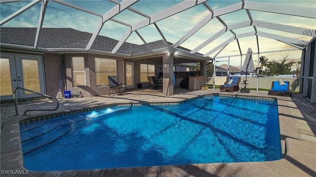 pool at dusk with a lanai and a patio