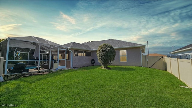 rear view of house with a lanai, a yard, and a swimming pool