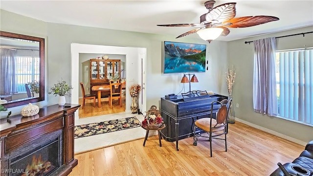 office area featuring a fireplace, light hardwood / wood-style floors, and ceiling fan