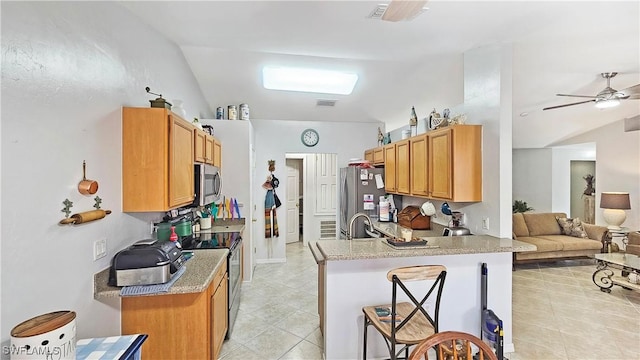 kitchen featuring light tile patterned flooring, appliances with stainless steel finishes, a breakfast bar, sink, and kitchen peninsula