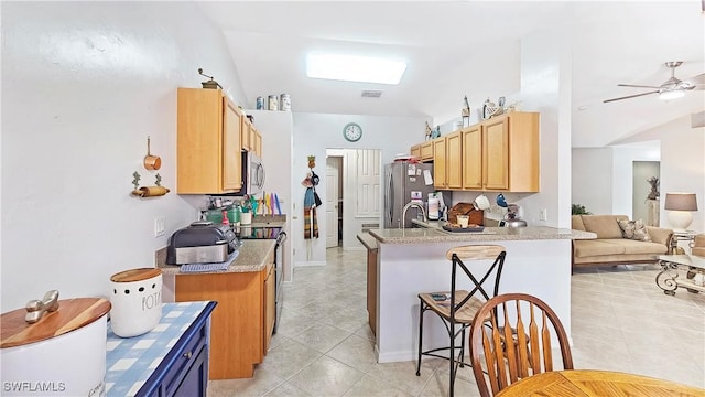 kitchen with light tile patterned flooring, sink, kitchen peninsula, ceiling fan, and stainless steel appliances