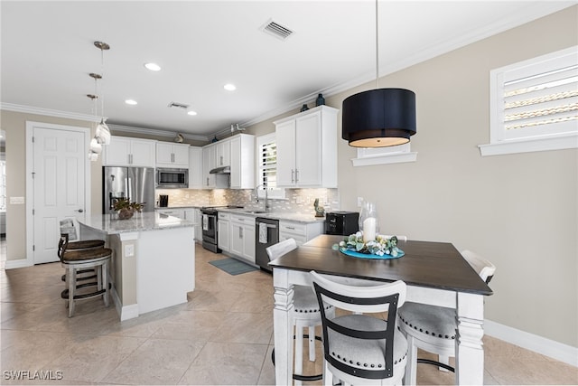 kitchen with stainless steel appliances, decorative light fixtures, white cabinetry, and a center island