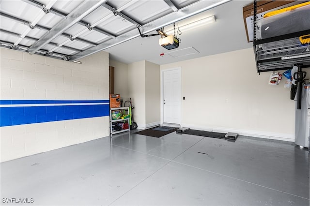 garage featuring a garage door opener, concrete block wall, and baseboards