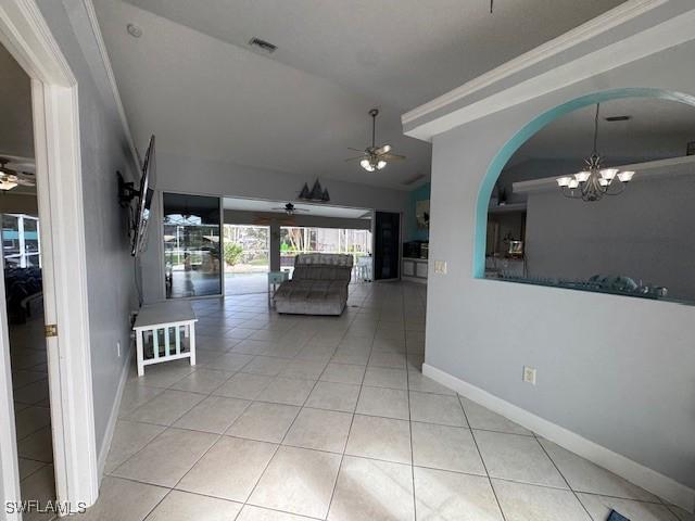 hall with light tile patterned floors, vaulted ceiling, and an inviting chandelier