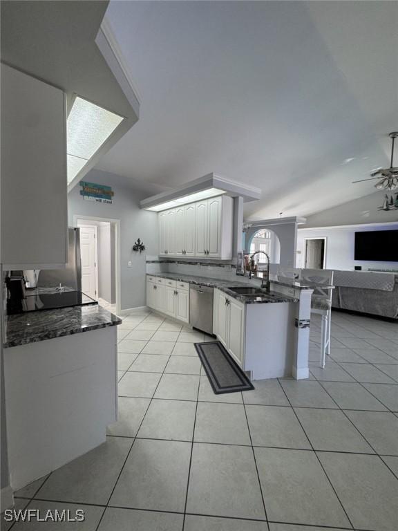 kitchen with white cabinetry, light tile patterned floors, stainless steel dishwasher, and sink