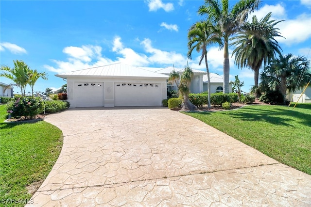 ranch-style home with stucco siding, a front yard, a standing seam roof, metal roof, and driveway