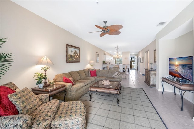 tiled living room featuring ceiling fan with notable chandelier, visible vents, and baseboards