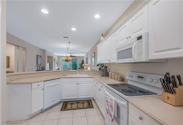 kitchen featuring light tile patterned floors, visible vents, a sink, white appliances, and a peninsula