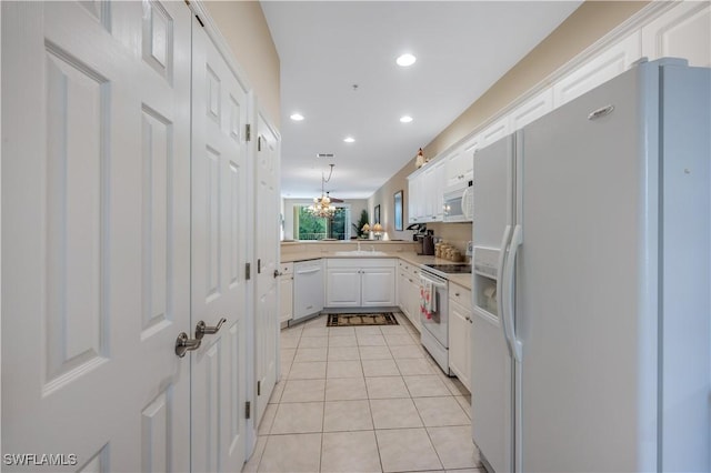 kitchen with light tile patterned floors, light countertops, white cabinetry, a sink, and white appliances