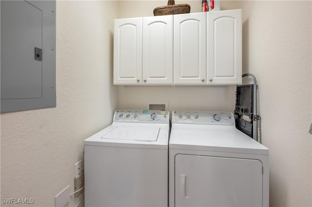 laundry area with a textured wall, separate washer and dryer, cabinet space, and electric panel