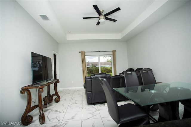dining space featuring ceiling fan and a tray ceiling
