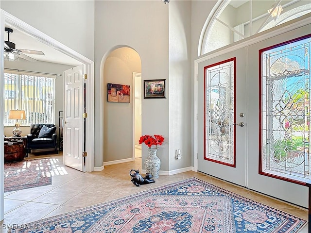 tiled entrance foyer featuring french doors, ceiling fan, and a high ceiling