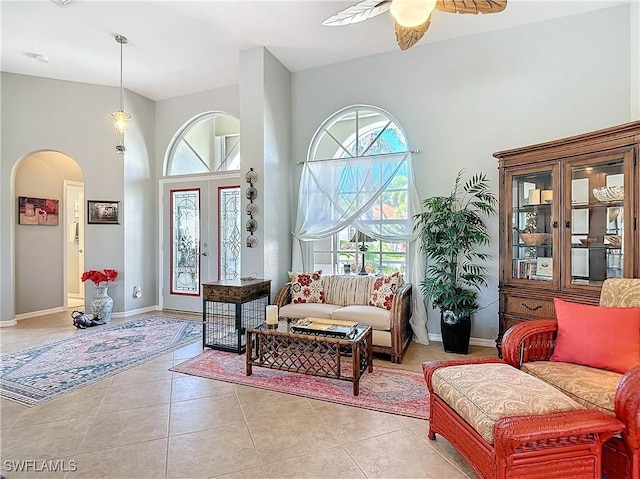 sitting room with a towering ceiling, ceiling fan, and light tile patterned floors