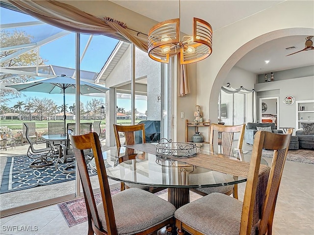 tiled dining space with ceiling fan, plenty of natural light, and a high ceiling