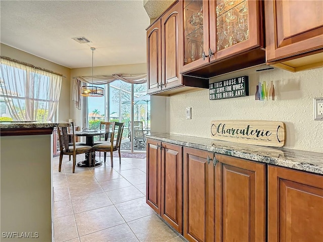 kitchen with hanging light fixtures, light stone countertops, light tile patterned flooring, and a textured ceiling