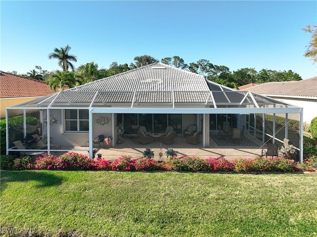 rear view of property featuring a lanai, a lawn, and a patio area