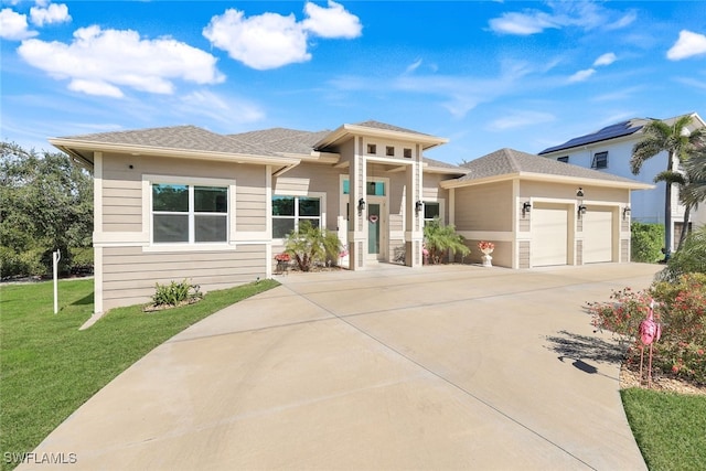 prairie-style home featuring a garage and a front lawn