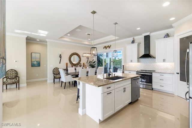 kitchen with white cabinetry, sink, stainless steel appliances, a center island with sink, and wall chimney exhaust hood