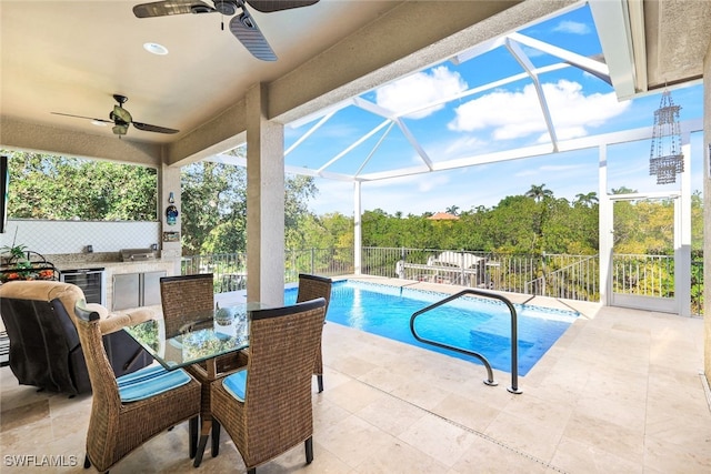 view of pool featuring an outdoor bar, ceiling fan, a patio, glass enclosure, and exterior kitchen