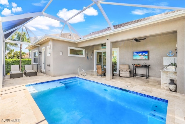 rear view of property featuring an outdoor kitchen, glass enclosure, ceiling fan, and a patio area