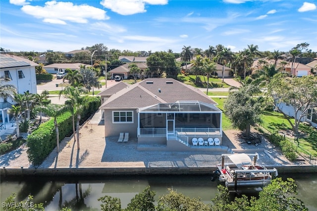 rear view of property featuring a water view, glass enclosure, and a patio area