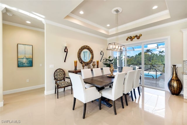 dining space with a notable chandelier, ornamental molding, and a raised ceiling