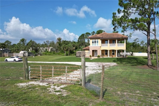 exterior space featuring a balcony, a fenced front yard, and a gate