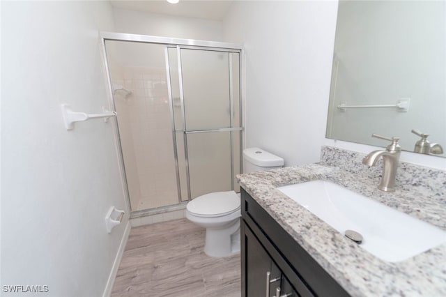 bathroom with vanity, toilet, an enclosed shower, and wood-type flooring