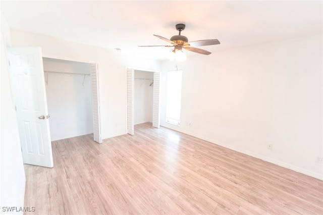 unfurnished bedroom featuring ceiling fan, light hardwood / wood-style floors, and two closets