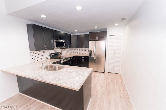 kitchen featuring appliances with stainless steel finishes, light stone counters, and kitchen peninsula