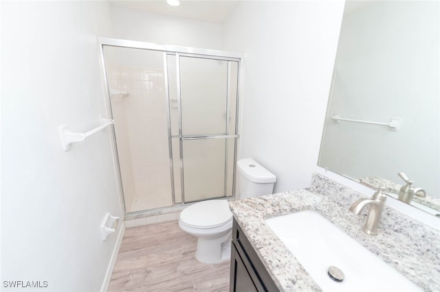 bathroom featuring hardwood / wood-style flooring, vanity, toilet, and a shower with door