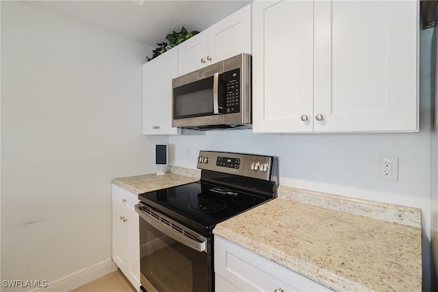 kitchen with white cabinetry, light tile patterned floors, light stone counters, and appliances with stainless steel finishes