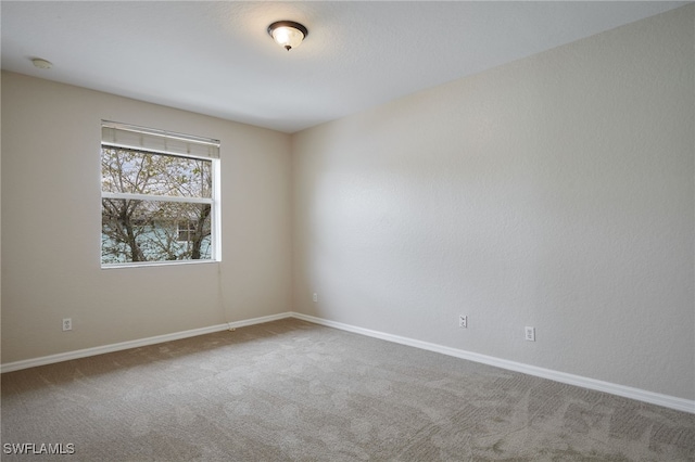 unfurnished room featuring carpet and baseboards