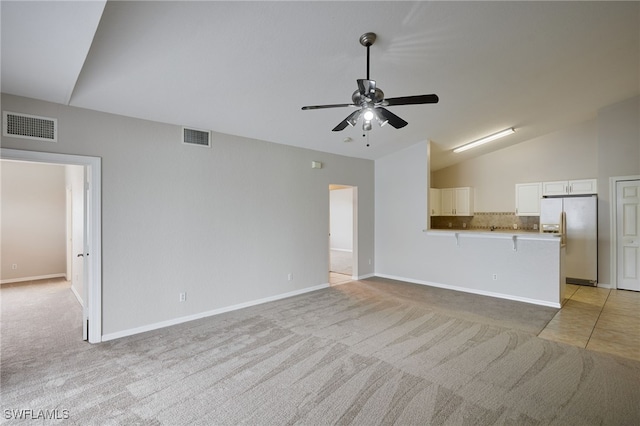 unfurnished living room featuring visible vents, vaulted ceiling, a ceiling fan, and light colored carpet